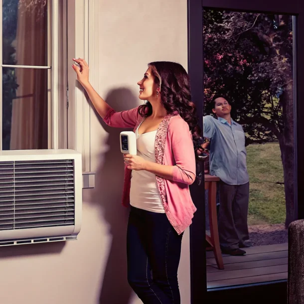Homeowner checking a thermostat while a heat pump warms the home