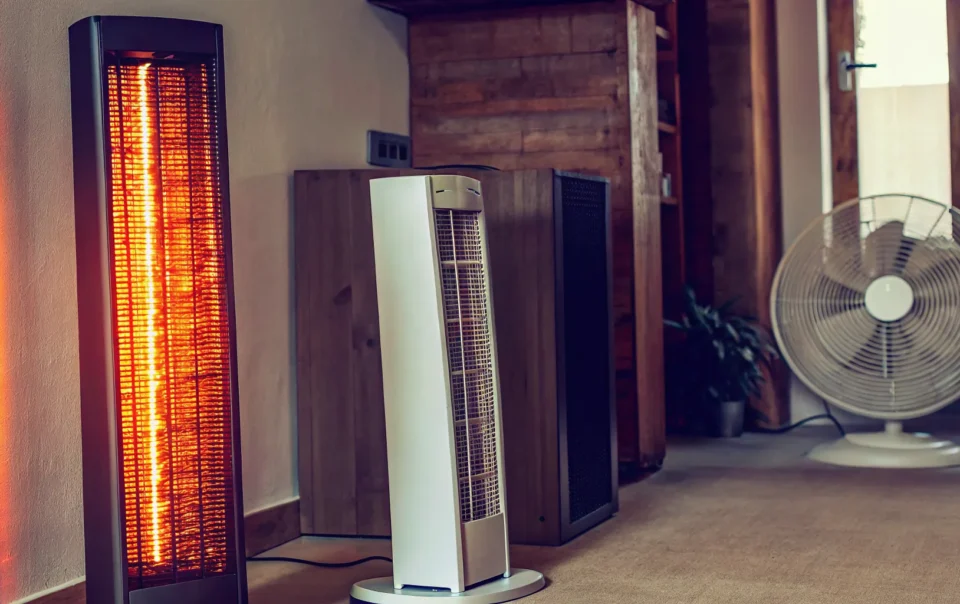 Different types of portable heaters, including a tower heater, placed in a living room.